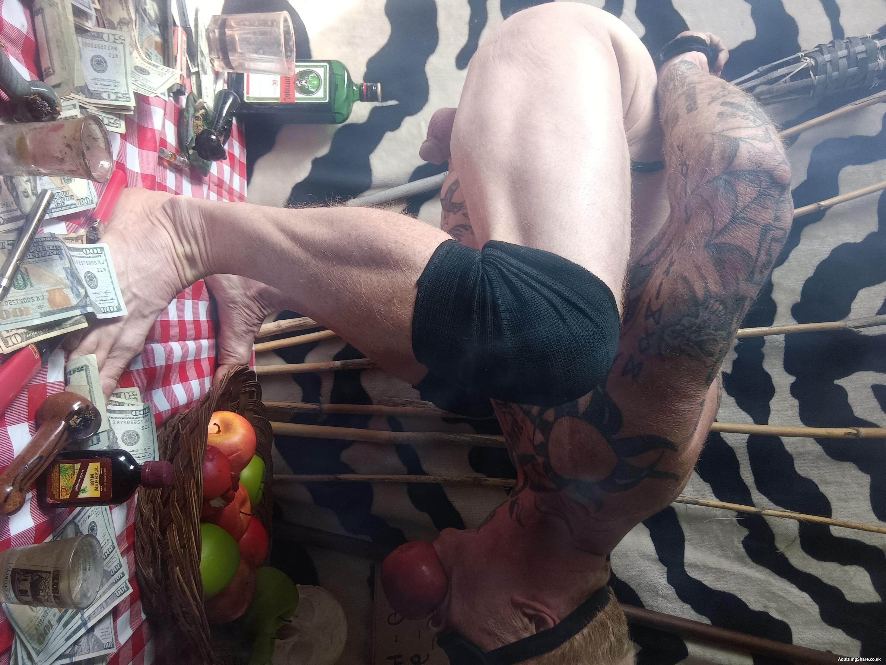 Tied and blindfolded, The Dancing Longpig avoids The Spit (BBQ) by biting a Red Apple over a Green Apple.